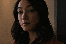 a woman with long dark hair is looking at the camera
