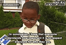 a young boy wearing glasses and a backpack is standing in front of a fence in a park .