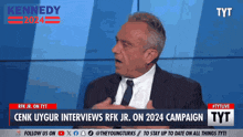 a man in a suit and tie is being interviewed on a tv show called kennedy 2024