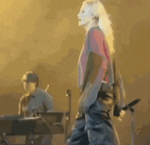 a woman is singing into a microphone while a man plays a keyboard in the background