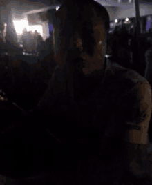 a blurry picture of a man in a dark room with a crowd in the background