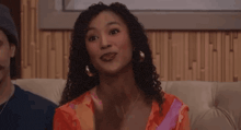 a woman is sitting on a couch with a man and making a face .