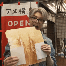 a man holding a piece of paper in front of an open sign