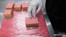 a person 's hand is reaching for a piece of cake that is wrapped in plastic wrap and made in animatica