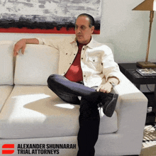 a man sits on a white couch with alexander shunnarah trial attorneys written on the bottom right