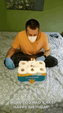 a man wearing a mask and gloves is sitting on a bed with a birthday cake made out of toilet paper