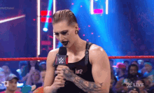 a woman in a wrestling ring holding a microphone with a wwe logo on it