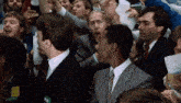 a group of men in suits and ties are sitting in a room .