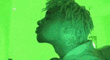 a person with dreadlocks is standing in front of a green wall .