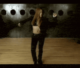 a woman in a black jacket is dancing on a wood floor