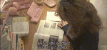 a woman is looking at a piece of paper on a desk with foreign writing on it