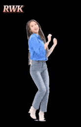 a woman in a blue shirt and jeans is dancing in front of a sign that says bagoiyan