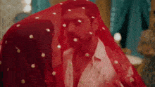 a woman is kissing a man on the cheek while he is covered in a red veil .