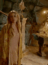 a woman in a yellow robe stands in front of a table