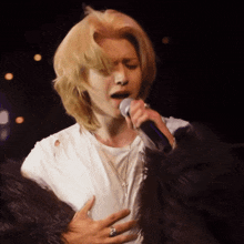a woman singing into a microphone while wearing a fur coat