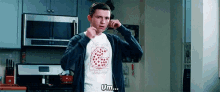 a man is standing in a kitchen wearing a t-shirt with a pizza on it .