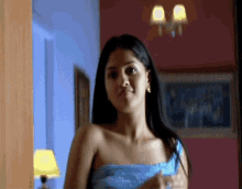 a woman in a blue off the shoulder top stands in a room