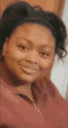 a woman with a ponytail is smiling for the camera while wearing a red shirt .