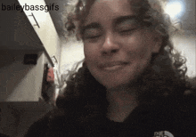 a woman with curly hair is wearing a black shirt with the north face on it