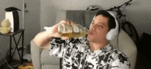 a man wearing headphones is drinking from a bottle .