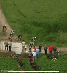 a group of cyclists are riding down a dirt road