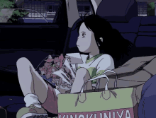 a girl is sitting in the back seat of a car holding a bag that says kinokuniya