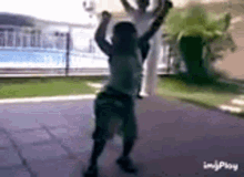 a young boy is holding a basketball over his head while another child looks on .