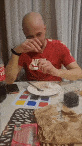 a man in a red nike shirt is sitting at a table eating food