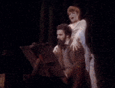 a man and a woman are standing next to each other in a dark room