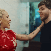 a woman in a red dress is touching the neck of a man