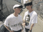 two young men standing next to each other one wearing a la mode t-shirt