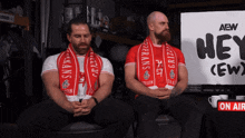 two men sitting in front of a sign that says hey ( ew )