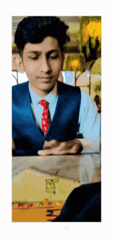 a young man in a suit and tie sits at a table with a cake that says best mom on it