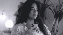 a black and white photo of a woman holding her phone