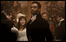 a man in a black suit stands in front of a crowd