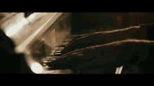 a close up of a person 's hands playing a piano in a dark room .