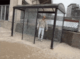 a man standing in front of a glass shelter that says ' trolley ' on it