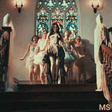 a group of women are dancing in front of a stained glass window and the word ms is on the bottom right