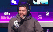 a man wearing headphones is talking into a microphone in front of a sign that says radio andy sirius