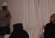a man wearing glasses and a beanie is standing next to a man in a black hoodie