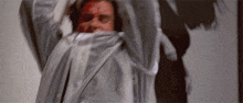 a man with blood on his face is wearing a gray jacket