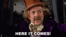 a man in a top hat and bow tie is saying here it comes !
