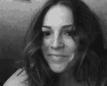 a black and white photo of a woman with long hair looking at the camera .