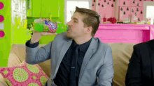 a man in a suit drinking from a bottle of fanta