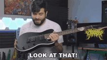 a man holding a guitar with the words look at that below him