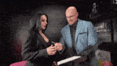 a man in a blue suit holds a clipboard next to a woman
