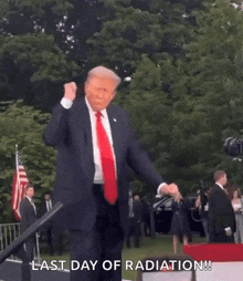 a man in a suit and tie is dancing in front of a crowd and says last day of radiation .