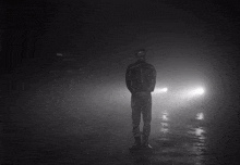 a man in a black jacket is standing in the fog