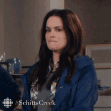 a woman is wearing a blue jacket with #schitts creek written on the bottom