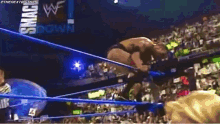 a wrestler is jumping over another wrestler in front of a crowd with a sign that says down